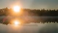 Scenic misty glowing sunrise over lake with large orange Sun, Sun rays in rising from water surface fog coast with trees, mirror Royalty Free Stock Photo