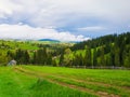 Scenic mountains nature and an old village of wooden cabins on the hills. Sunny spring day with green grass, flowering meadows and Royalty Free Stock Photo