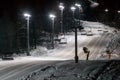 Scenic night view of illuminated snowy ski track with chair ski lift. Night skiing service at Sochi Gorky Gorod winter mountain re