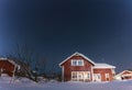 Scenic night view of traditional Swedish red wooden house in countryside with apple tree, shed. Very frosty starry night with deep Royalty Free Stock Photo