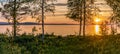 Scenic Panorama - Sunset over Umea river Mountains, summer sky with clouds highlighted by orange red Sun. Blurry foreground with Royalty Free Stock Photo