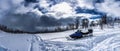 Scenic panorama view of snow mobile standing in deep snow at mountain slope at the beginning of snow storm, wild mountain birches