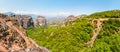 Scenic panoramic landscape view on Meteora rock formations cliffs and peaks surrounded by vibrant green plants and trees in Greece