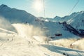 Scenic panoramic view of alpine peaks with ski lift ropeway on hilghland mountain winter resort and snow making machines on bright