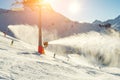 Scenic panoramic view of alpine peaks with ski lift ropeway on hilghland mountain winter resort and snow making machines on bright