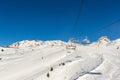 Scenic panoramic view of alpine peaks with ski lift ropeway on hilghland mountain winter resort and snow making machines on bright