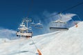 Scenic panoramic view of alpine peaks with ski lift ropeway on hilghland mountain winter resort and snow making machines on bright