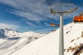 Scenic panoramic view of alpine peaks with ski lift ropeway on hilghland mountain winter resort and snow making machines on bright