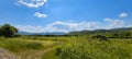 Scenic panoramic view of idyllic rolling hills landscape with blooming meadows and snowcapped alpine mountain peaks in the Royalty Free Stock Photo