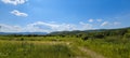 Scenic panoramic view of idyllic rolling hills landscape with blooming meadows and snowcapped alpine mountain peaks in the Royalty Free Stock Photo