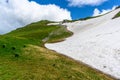 Scenic panoramic view of idyllic rolling hills landscape with blooming meadows and snowcapped alpine mountain peaks in Royalty Free Stock Photo