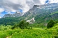 Scenic panoramic view of idyllic rolling hills landscape with blooming meadows and snowcapped alpine mountain peaks in Royalty Free Stock Photo