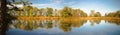 Scenic panoramic view of a tranquil lake surrounded by beautiful autumn trees during daytime Royalty Free Stock Photo