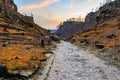 Scenic pathway through rocky canyon at sunset with autumn foliage and bare trees Royalty Free Stock Photo