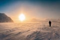 Scenic picture of large Sunset halo in winter mountains, strong snow drift wind. A person in warm black snowmobile overall and