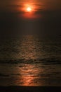 Scenic red orange Sunset with Sun hiding in clouds, glowing light line crosses Sun disk horizontally, vertical orientation photo. Royalty Free Stock Photo