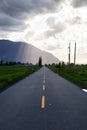 Scenic Road in a small town with Mountain in the Background during a dramatic sunny and cloudy evening