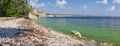 Scenic sea view from pebble beach. Beautiful summer background. Amazing landscape with blue sky, steep cliffs and picturesque bay.