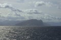 Scenic seascape with the silhouettes of the mountains on horizon in light haze. Abstract view of the sea and the land. Travel and Royalty Free Stock Photo