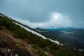 Scenic shot of an escalating landscape covered with dense trees and with a cloudscape