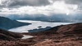 Scenic shot of a lake surrounded by mountains and valleys under a cloudy sky with a heavenly effect