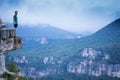 Scenic shot of a man standing on the edge of a cliff overlooking mountainous scenery Royalty Free Stock Photo
