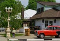 Scenic street of Arkhipo-Osipovka village with red retro car Moskvich 407 near cafe