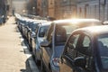 Scenic sunlit view row parked cars on busy city street in european city. Sidewalk parallel side parking full of vehicles Royalty Free Stock Photo