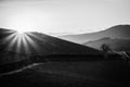 Scenic sunrise over mountains black and white. Mountain road in the morning monochrome. Beautiful morning with sun rays over hills