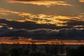 Scenic sunrise with yellow and dark clouds in the sky above the forest Royalty Free Stock Photo