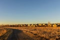 Scenic sunset landscape with a creek, houses, and bare trees Royalty Free Stock Photo