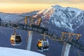 Scenic sunset landscape of gondola cable way ski lift of Gorky Gorod mountain ski resort in Sochi at winter with snowy Caucasus mo