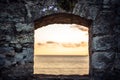 Scenic sunset over sea through window of old ruins with dramatic sky and perspective view with effect of light at the end of tunne Royalty Free Stock Photo