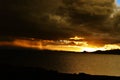 Scenic sunset photo features an expanse of water with dark, gathering clouds in the sky