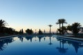 Scenic sunset by the sea, blue pool and palm trees in a hotel in Royalty Free Stock Photo