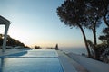 Scenic sunset view of an infinity swimming pool with an ocean background ocean. Luxury outdoor pool on a deck, patio Royalty Free Stock Photo