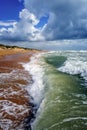 Scenic vertical landscape of sandy Black Sea beach by Anapa resort, Russia. Stormy waves splashing against beach sand on blue sky