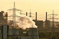 Scenic view of air pollution coming from an industrial plant with transmission posts during sunset