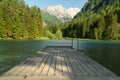 A scenic view of the alps taken at Jezersko lake, Slovenia. Scenic background and nice water reflection with wooden pier