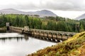 A scenic view of arch curved Laggan Dam with Scottish Highlands in background, Scotland