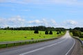 Scenic view of asphalt road near a green field of hay bales in the countryside Royalty Free Stock Photo