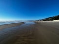 Scenic view of the beautiful ocean against a blue sky captured from a sandy shore Royalty Free Stock Photo