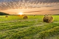 Scenic view at beautiful spring sunset in a green shiny field with green grass and golden sun rays, deep blue cloudy sky on a Royalty Free Stock Photo