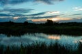 Scenic view of beautiful sunset above the lake at cloudy sky and silhouette grass field. Landscape of sunset and blue sky reflecte Royalty Free Stock Photo