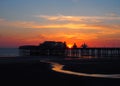 Scenic view of blackpool north pier in glowing red evening light at sunset with illuminated pink and yellow sky and clouds Royalty Free Stock Photo