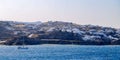 Scenic view of boat sailing in the open sea with white coastal houses on the background in Mykonos Royalty Free Stock Photo