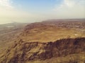 Scenic view of canyon from the top of the Masada National Park. Rock plateau against cloudy sky and the coast of the Dead sea at Royalty Free Stock Photo