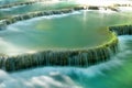 Scenic view on a cascaded Kuang Si waterfall with turquoise water on a sunny day.