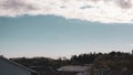 Scenic view of a cloudy blue sky above green trees and rooftops of houses