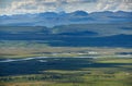 Scenic view of the distant Denali Highway, the green Maclaren River valley with river and lakes, a sky with summer clouds, taken f